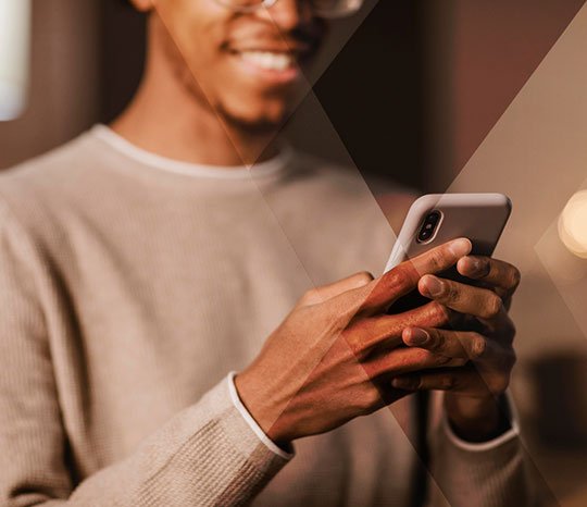 Homem negro usando um smartphone dentro de casa